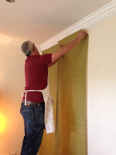 Man placing gold wallpaper on a wall